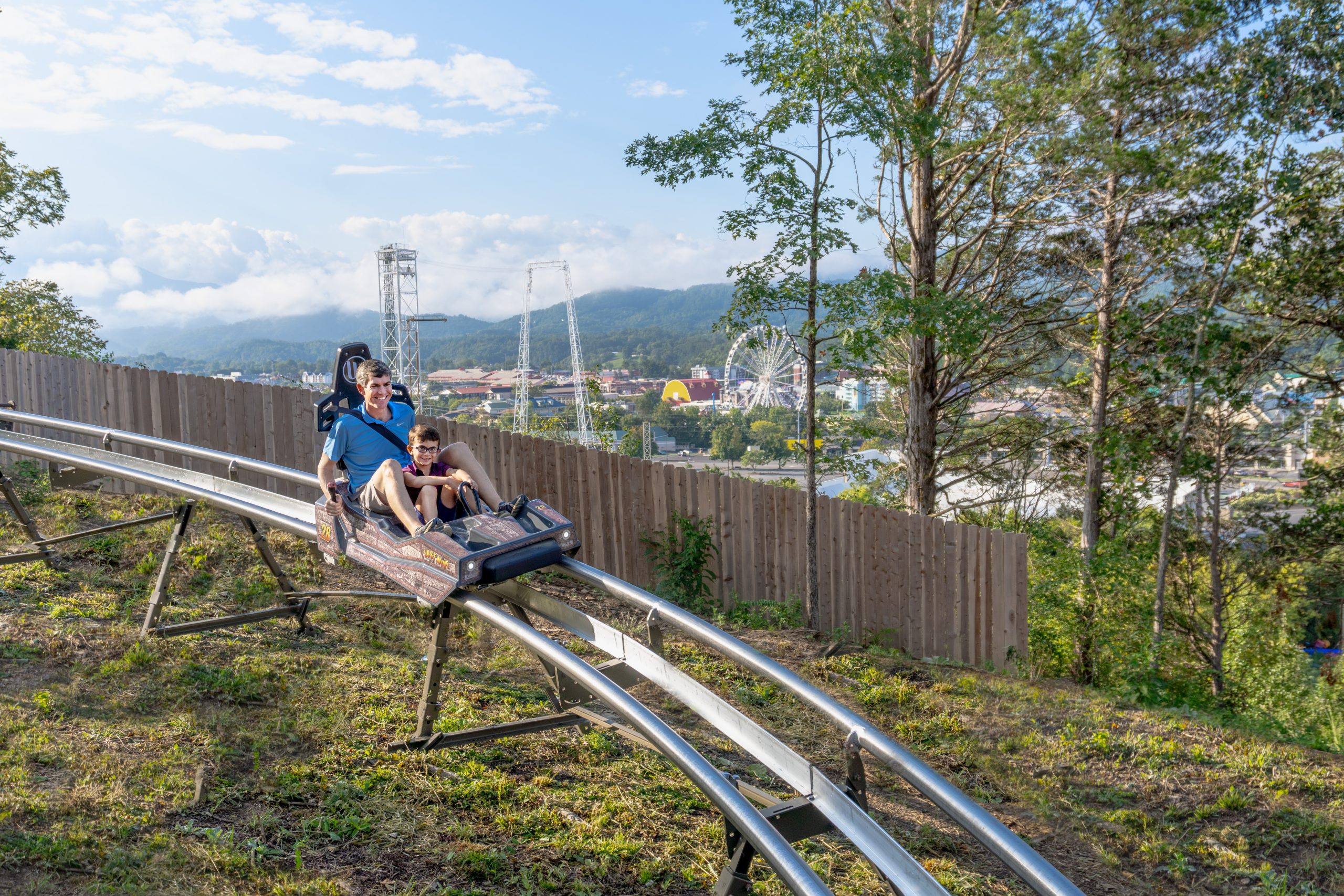 father and son riding the Lost Mine mountain coaster with scenic views of the Smoky Mountains in the background